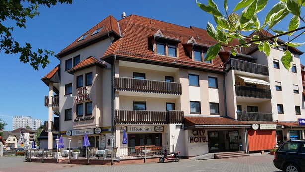 Een hotel met meerdere verdiepingen, voorzien van balkons, een restaurant en een parkeerplaats.