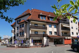 A multi-story hotel with balconies, a restaurant, and a parking area.