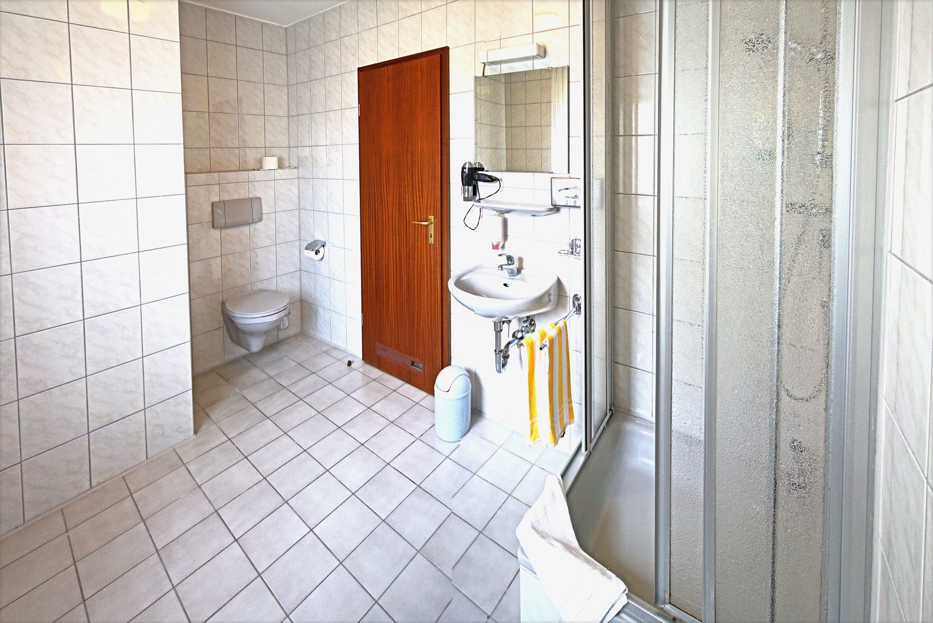 Un baño con inodoro, lavamanos y zona de ducha.