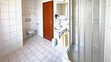 Un baño con inodoro, lavamanos y zona de ducha.