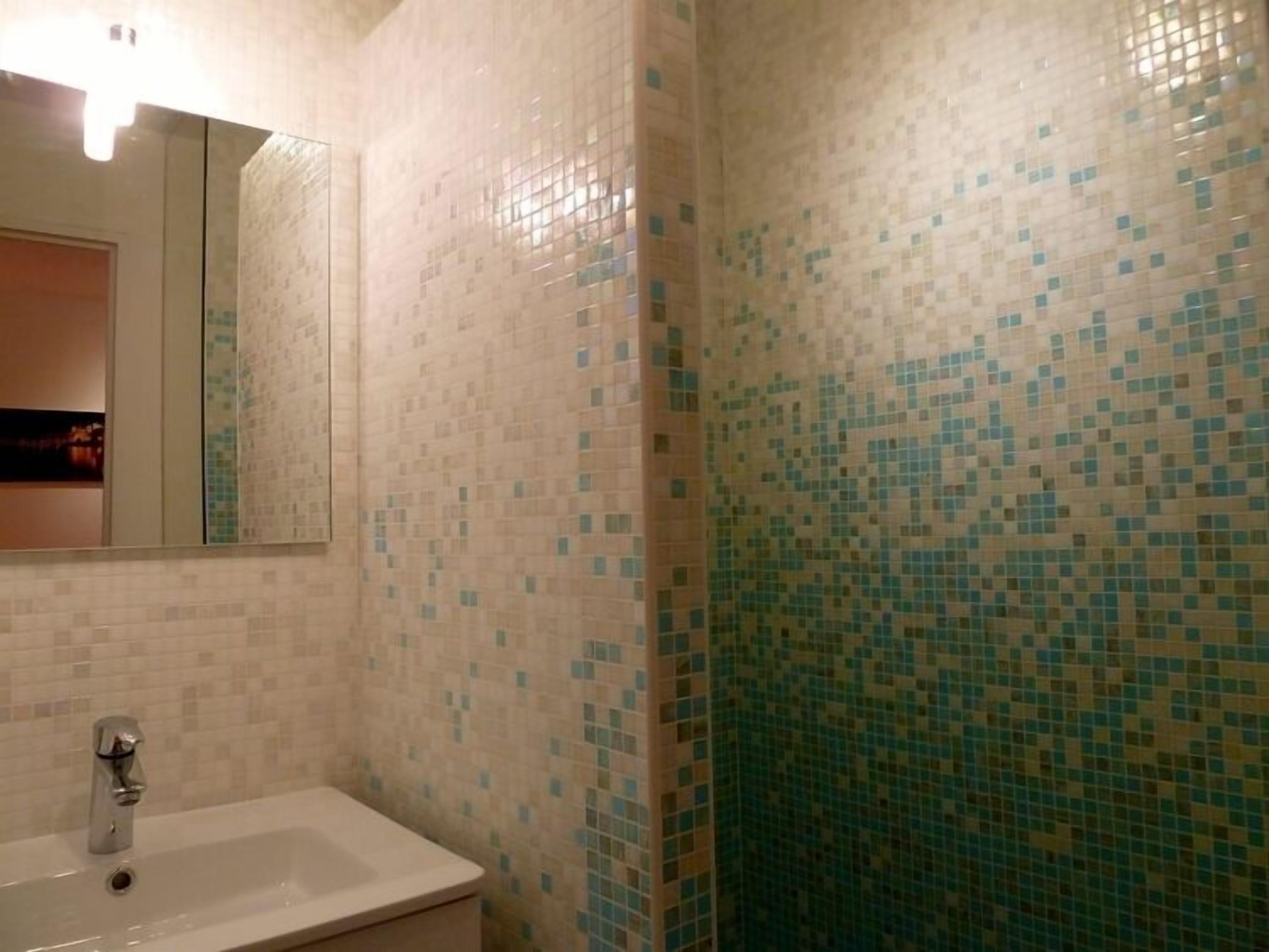 A bathroom with a sink, mirror, and tiled walls.