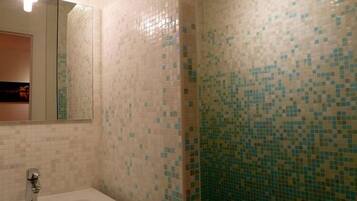 A bathroom with a sink, mirror, and tiled walls.