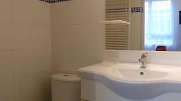 Un baño con lavamanos blanco, espejo y retrete.