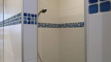 Un espace douche avec des carreaux blancs et une bordure en mosaïque bleue.