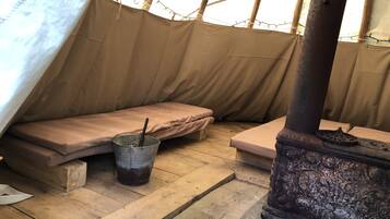 Simple, functional space with a metal bucket, wooden stool, and metal stove.