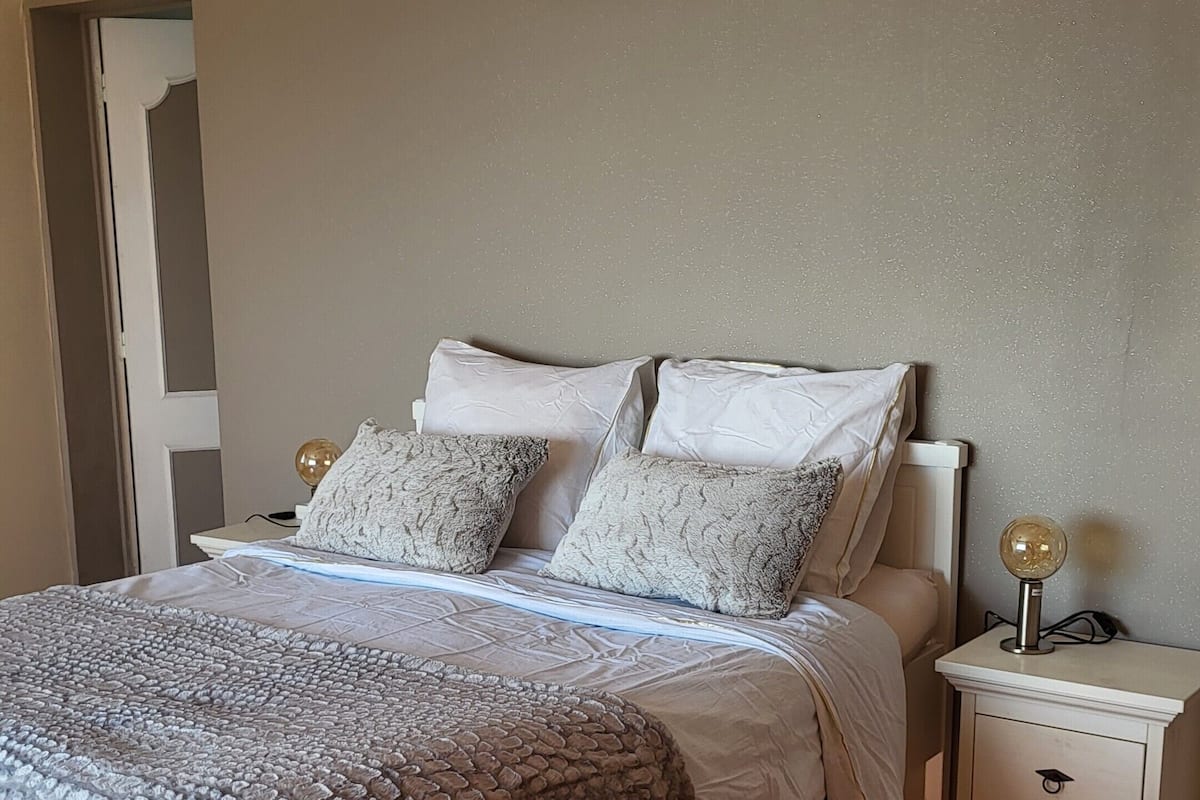 Un dormitorio con cama, mesitas de noche y lámpara de noche.