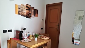 A dining area with a wooden table and chairs, a coffee maker, and decorative items on the table. - Bed & Breakfast da Luca (Bonassola)