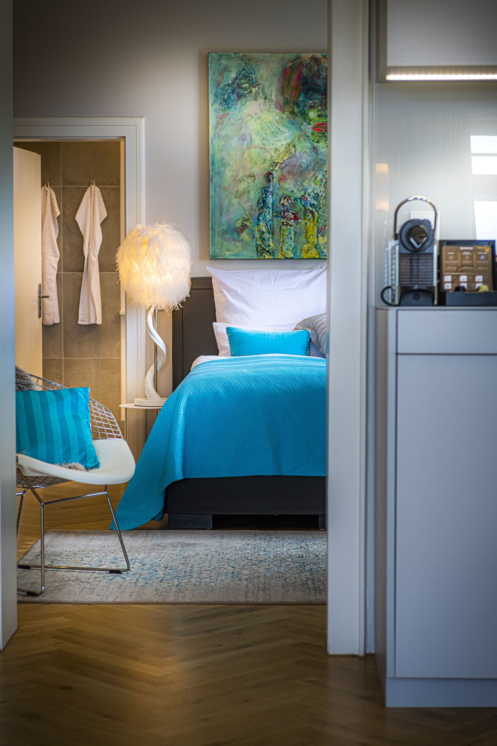 Une chambre à coucher moderne avec un lit, une chaise, une lampe et un tableau au mur.
