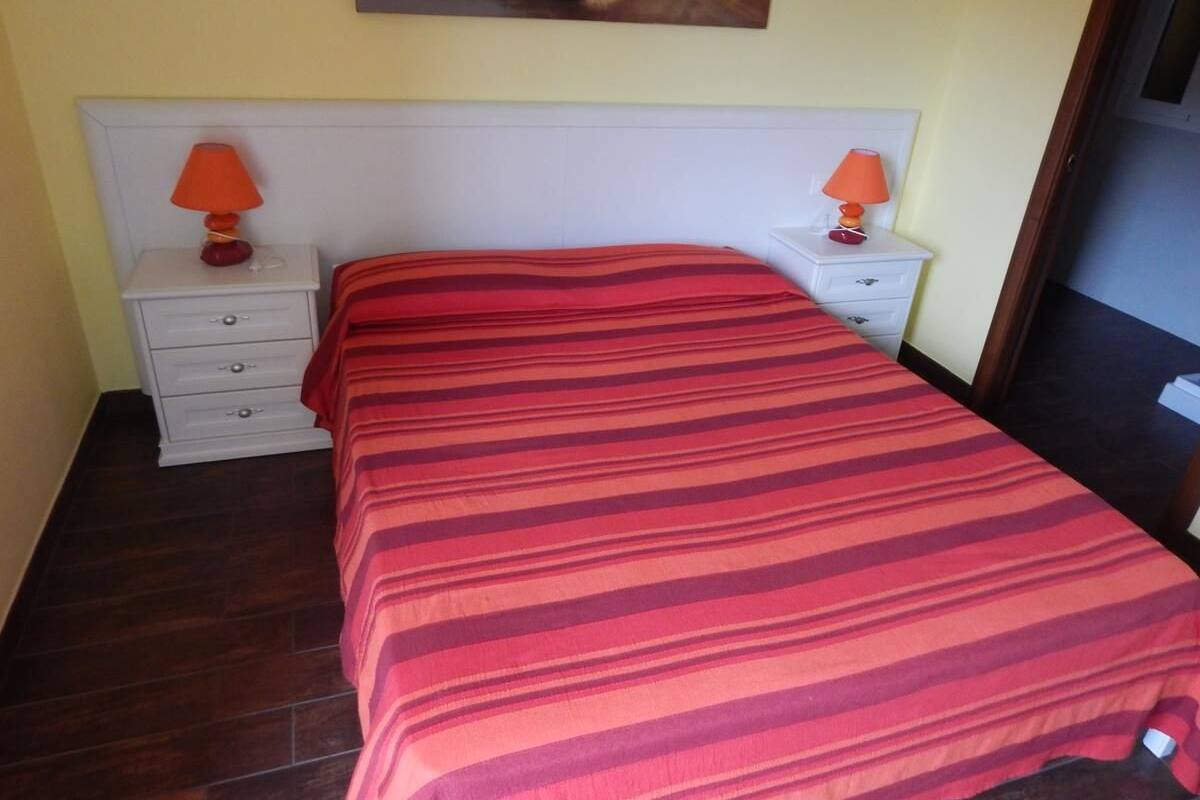 A bedroom with a bed, two nightstands, and a painting on the wall.