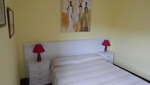 Une chambre à coucher avec un lit, deux tables de chevet avec des lampes, une commode et un tableau au mur.