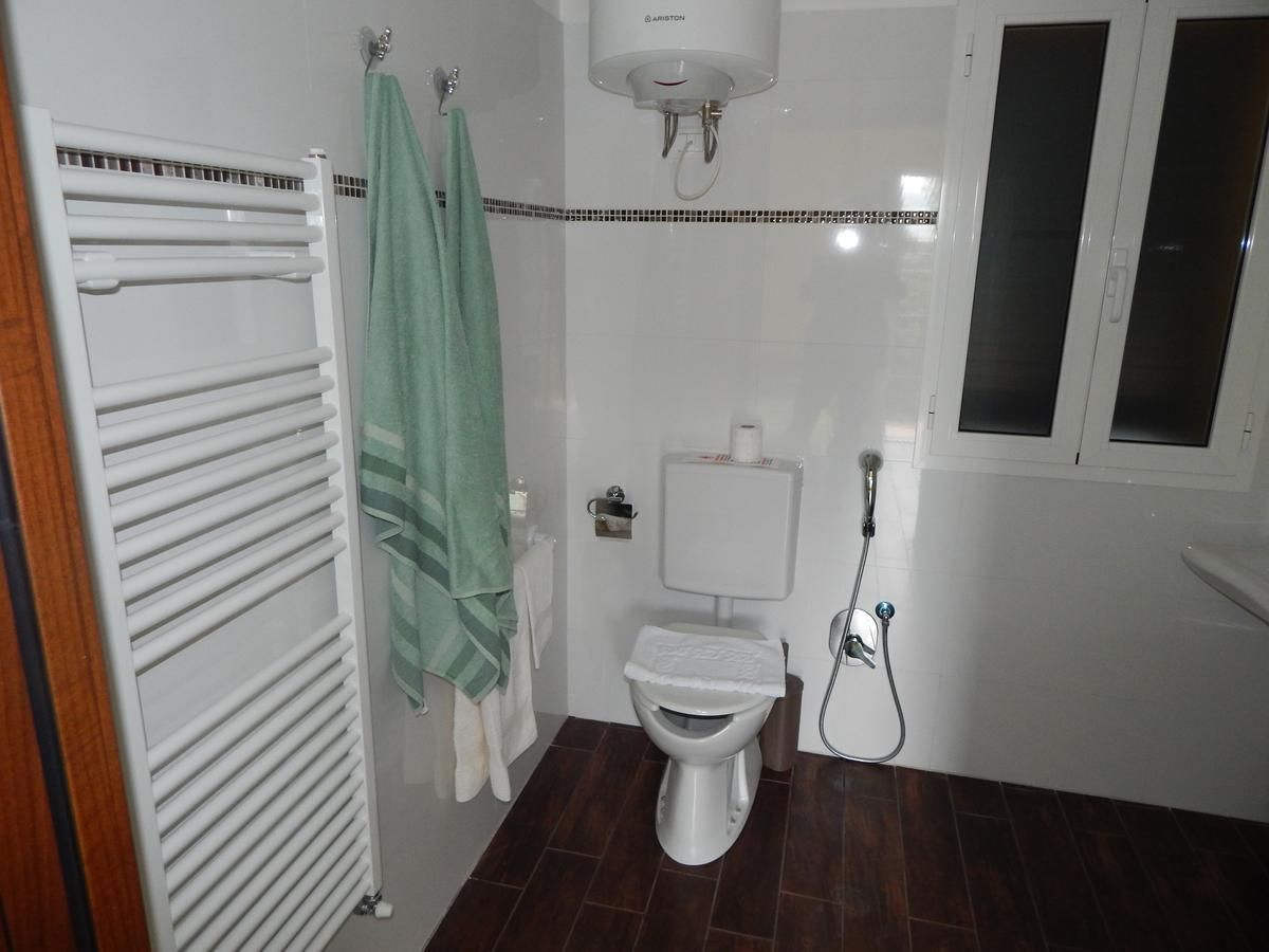 A bathroom with a toilet, a towel rack, a shower, and a radiator.