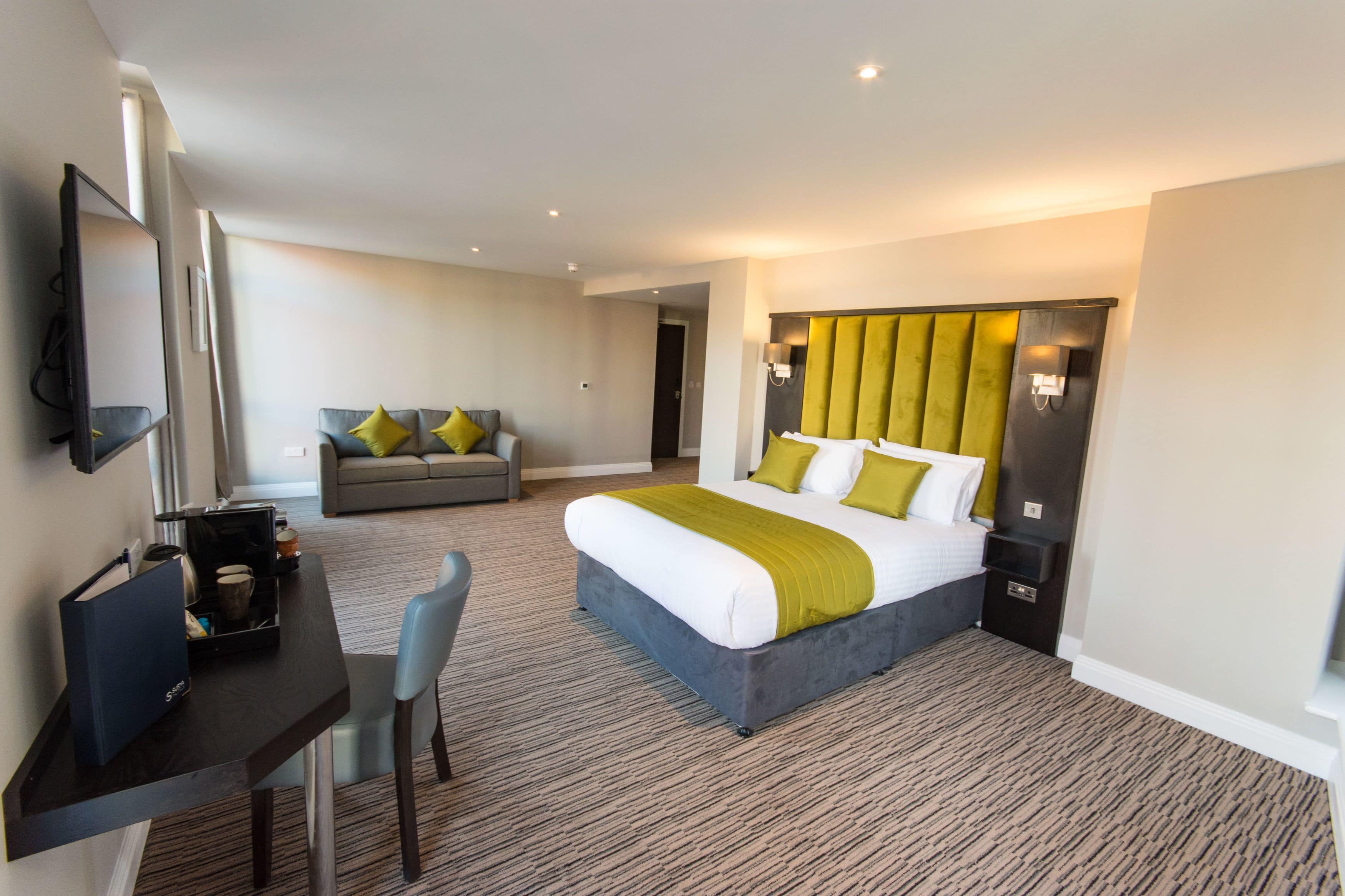 Een hotelkamer met een bed, een bureau met stoel, een bank en een televisie.