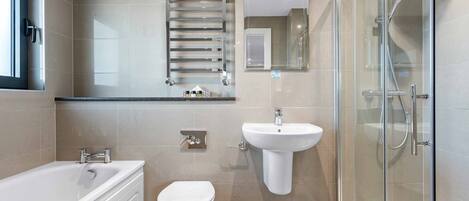 Een moderne badkamer met bad, toilet, wastafel en douchecabine met glazen wanden.