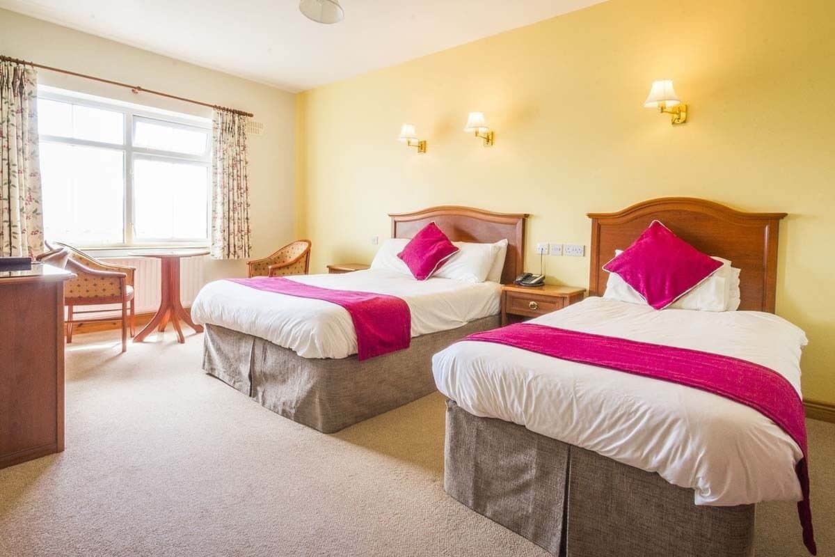 A hotel room with two beds, a desk, and a chair.