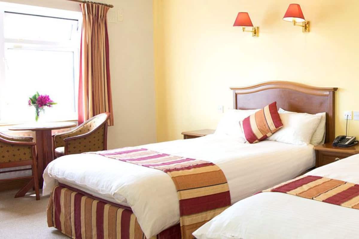 A hotel room with two beds, a desk, and a chair.