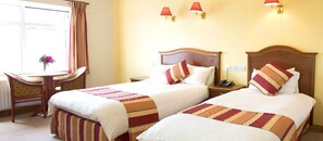 Een hotelkamer met twee bedden, een bureau en een stoel.