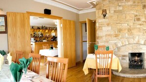 Un espace repas avec des meubles en bois, une cheminée en pierre et un bar situé au fond de la pièce.