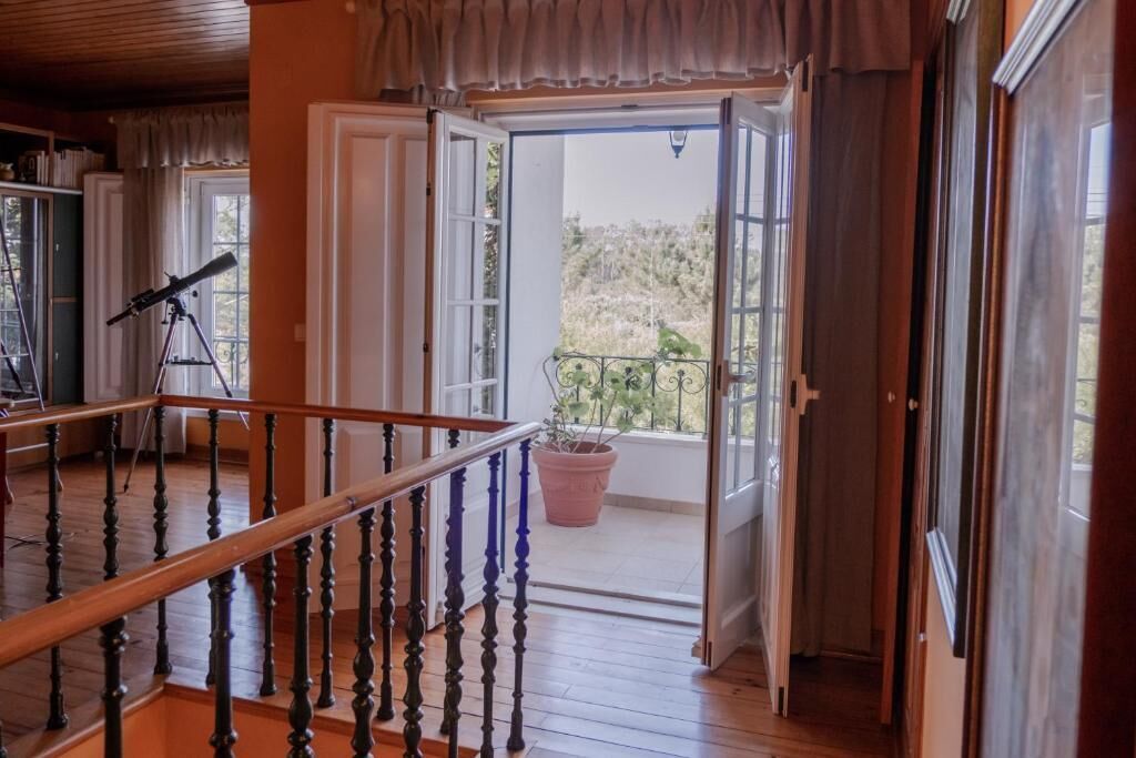 A wooden staircase leading to a balcony with a telescope on the left.