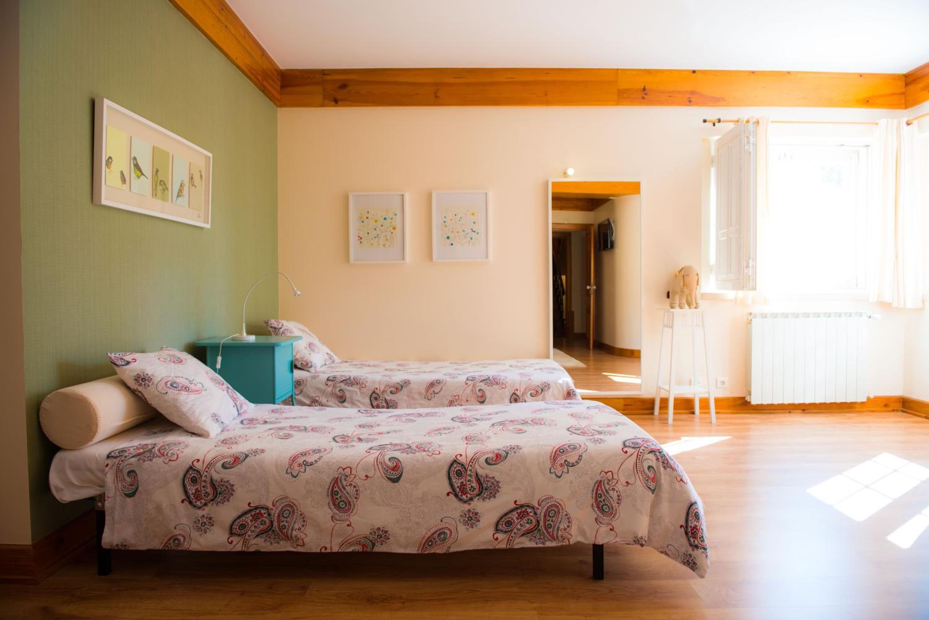 A bedroom with two beds, a wooden ceiling, and a view of a hallway.