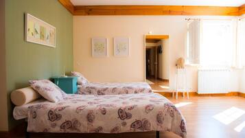 A bedroom with two beds, a wooden ceiling, and a view of a hallway.