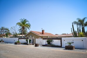 A house with a red-tiled roof, white walls, and a gravel driveway.