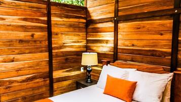 A wooden room with a bed, a nightstand, and a window.