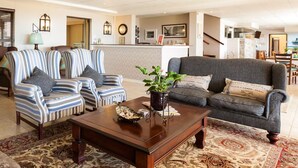 Un salon avec des fauteuils à rayures, un canapé gris, une table basse en bois et un tapis à motifs.