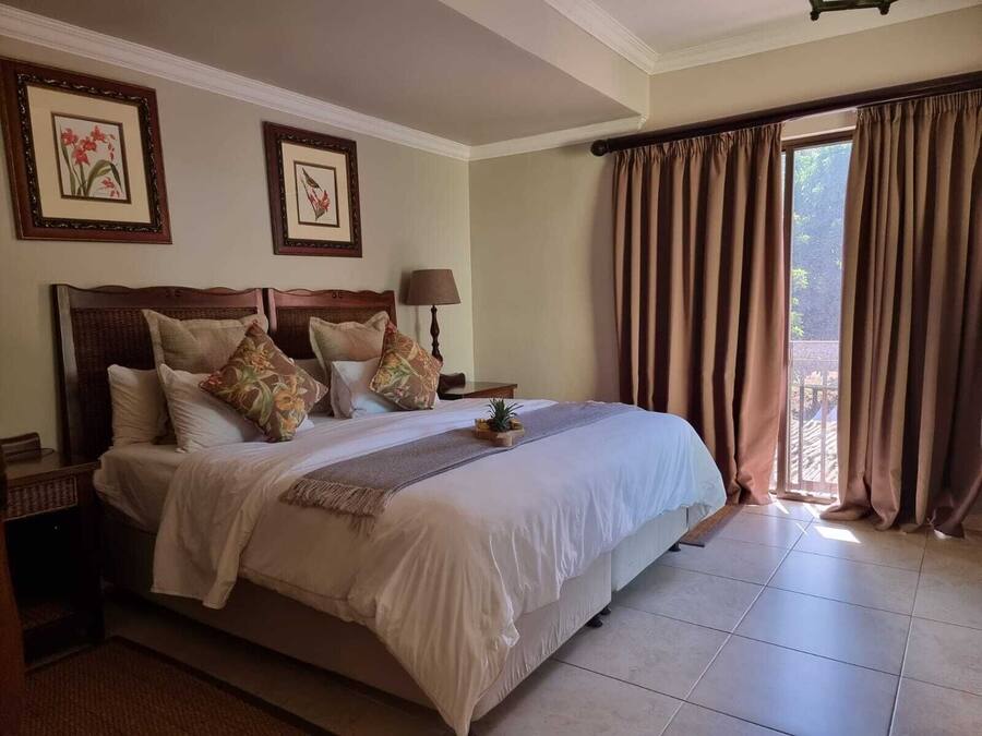A neatly made bed with a wooden headboard, a bedside table with a lamp, and two framed pictures on the wall.