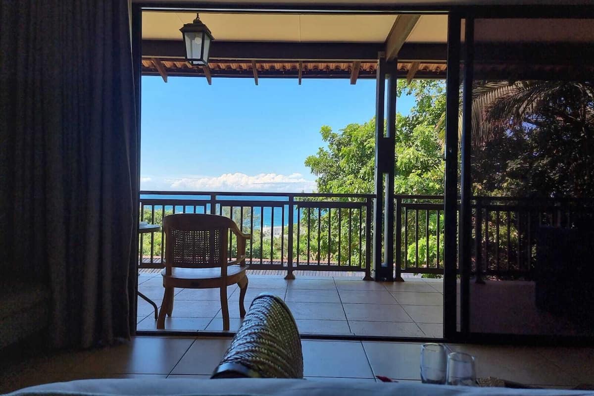 A balcony with a view of the sea, a chair, and a table.