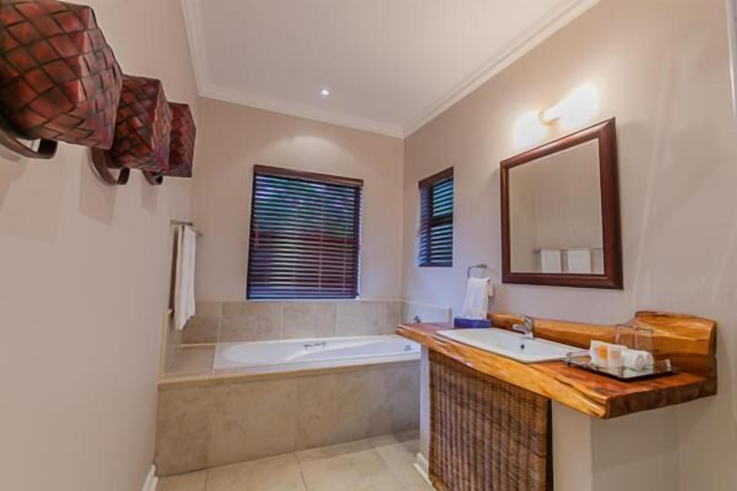 A bathroom with a bathtub, a wooden vanity, and a large mirror.
