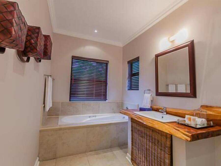 A bathroom with a bathtub, a wooden vanity, and a large mirror.