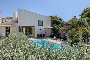 Un bâtiment moderne doté d’une piscine, d’un espace extérieur aménagé et d’une végétation luxuriante.