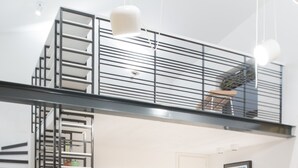 Ein moderner Wohnraum mit einer Treppe zu einem Erkerbereich, einer Sofagarnitur, einem Couchtisch und einem Fernseher.