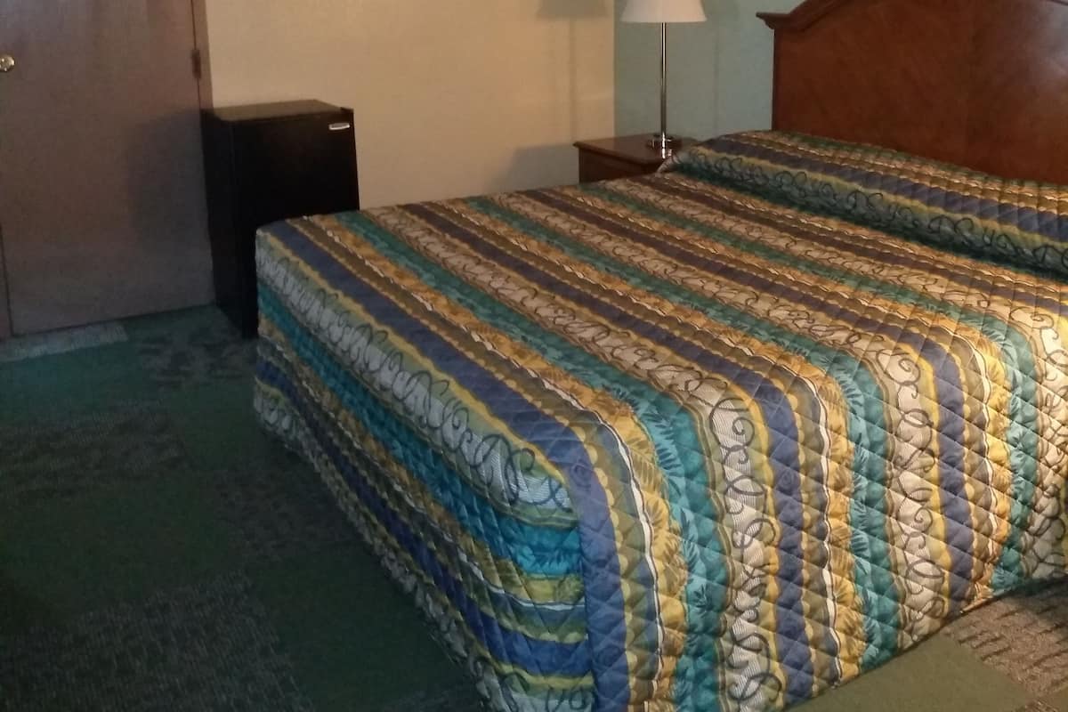 Ein Hotelzimmer mit Bett, Nachttisch, Lampe und Tür.
