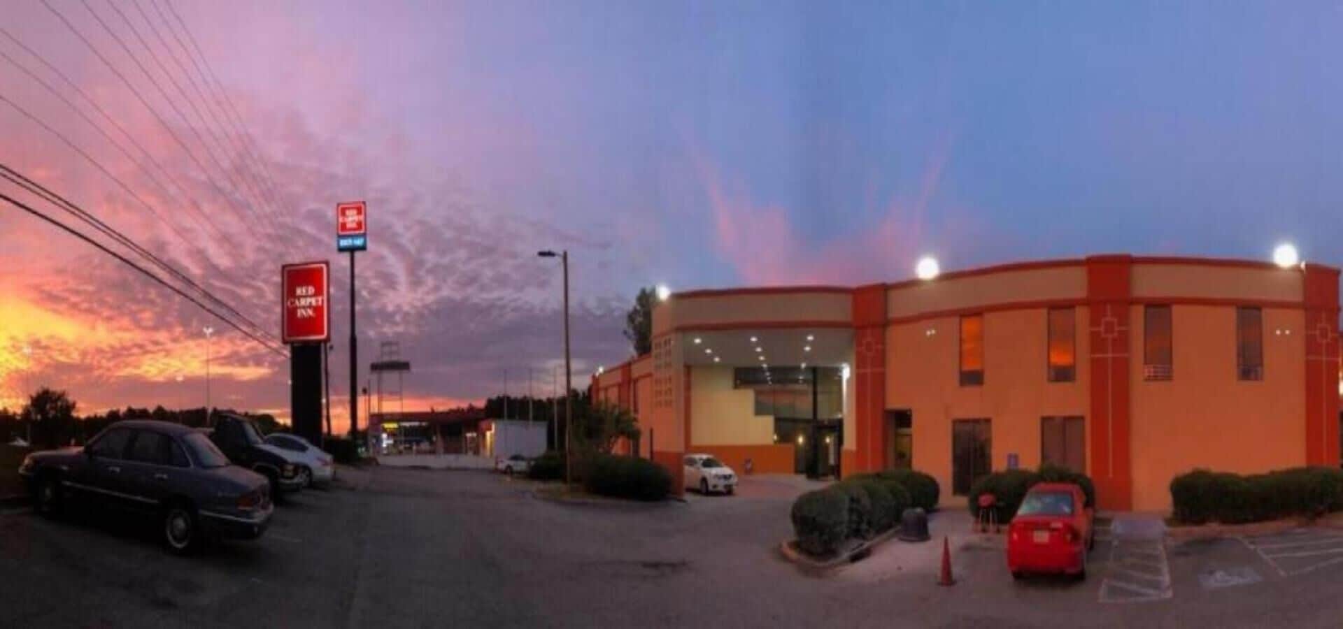 A Red Carpet Inn with a parking lot and a sunset sky.