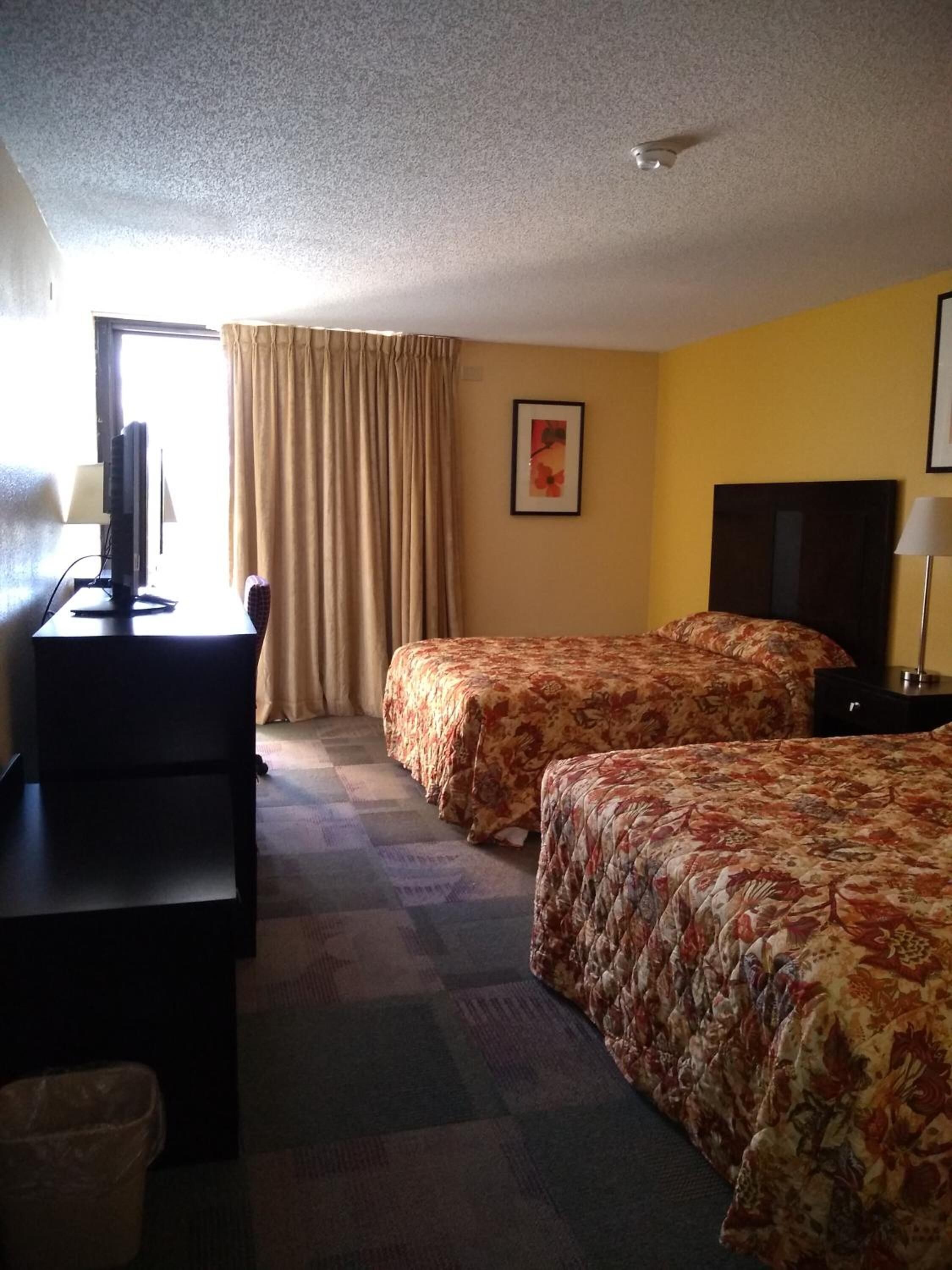 Une chambre d’hôtel avec deux lits, un bureau, une chaise et un téléviseur.