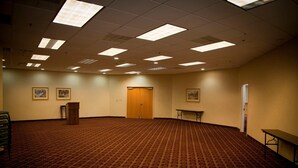 A large, carpeted room with a wooden podium, framed pictures on the walls, and a door at the back. - Red Carpet Inn (Macon)