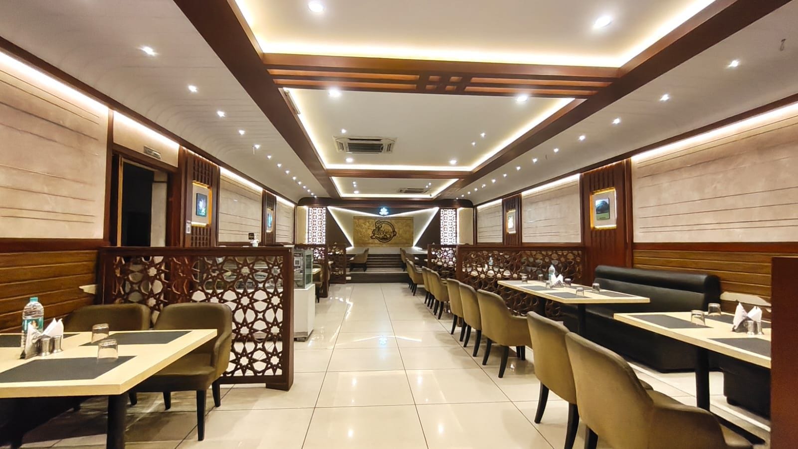 Un restaurante con mesas, cabinas y piso de baldosas, y una pared decorativa central.