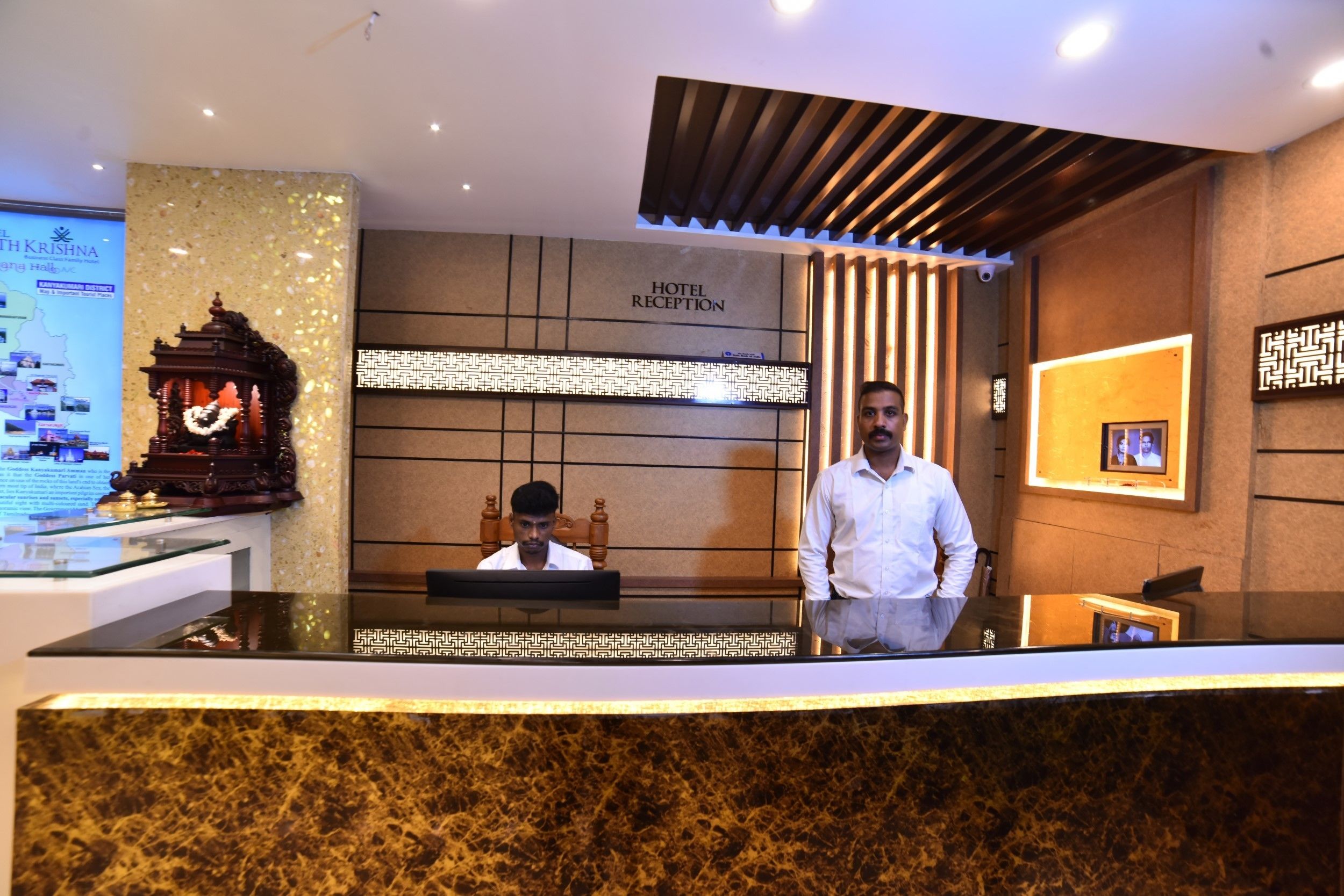 Un área de recepción de hotel con un mostrador de mármol, un escritorio de recepción y una pared decorativa con un letrero que dice "HOTEL RECEPTION".