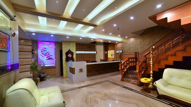 Un vestíbulo de hotel con una recepción, una escalera y zonas de estar.
