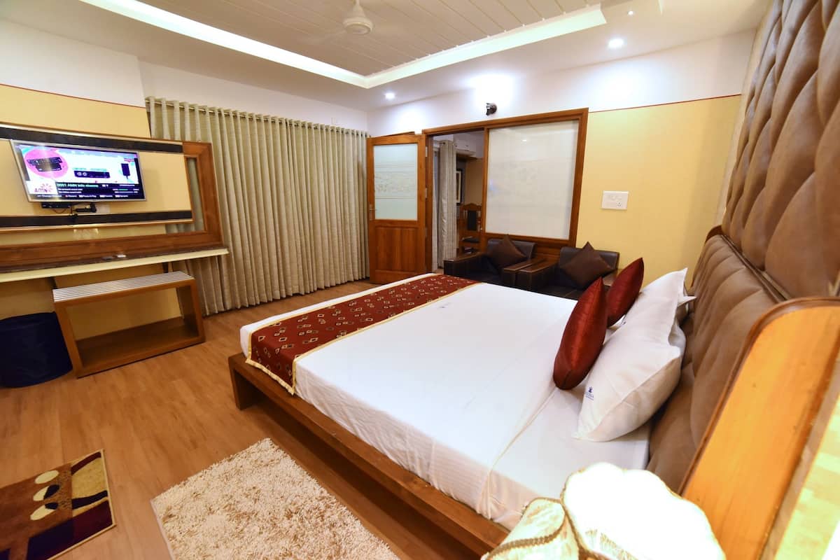 A hotel room with a large bed, a TV mounted on the wall, a wooden desk, and a sliding door closet.