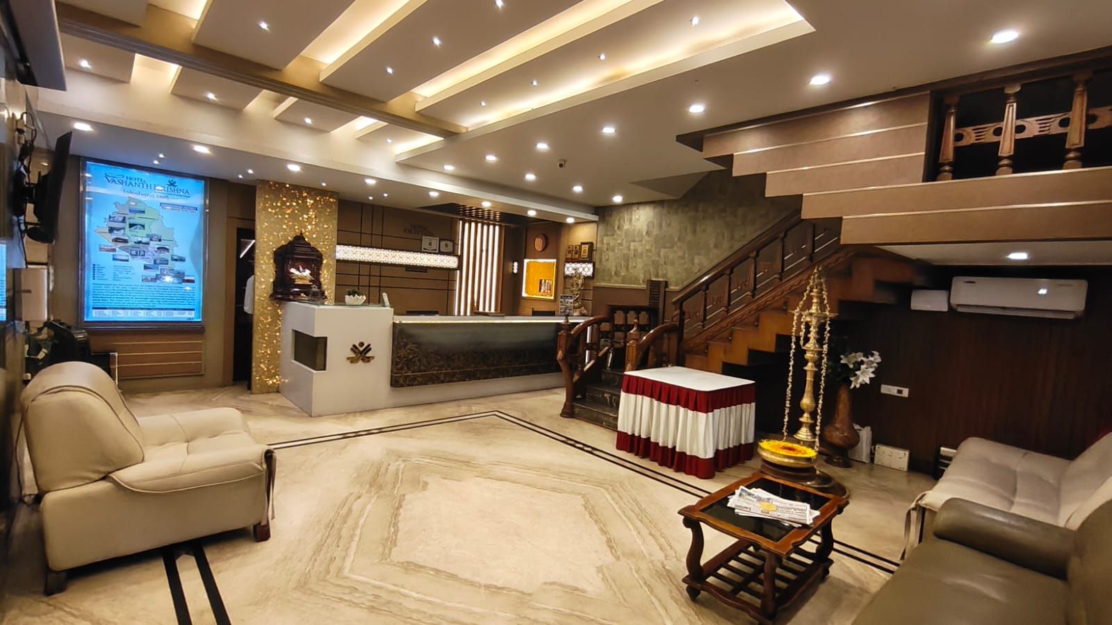 Un vestíbulo de hotel con una recepción, zona de estar y una escalera.