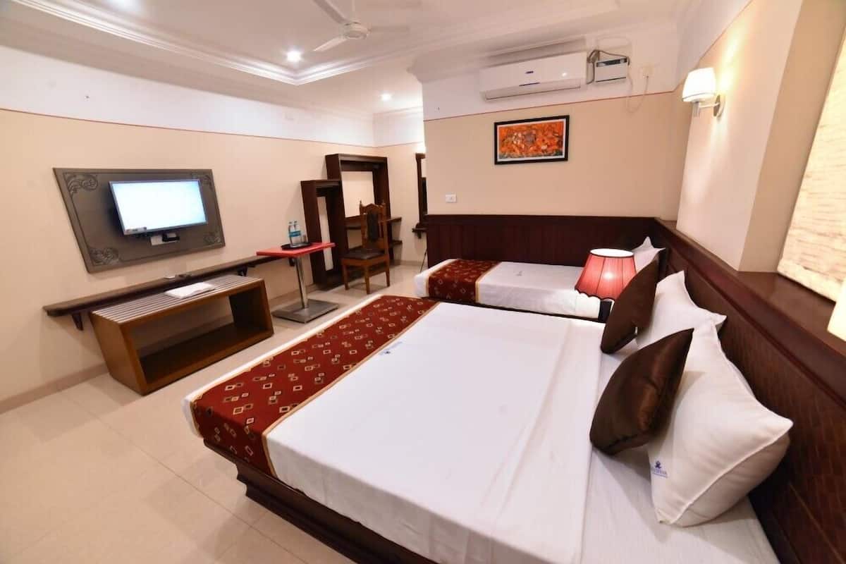 A hotel room with two beds, a TV, a desk, and a chair.