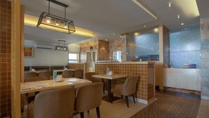 Un restaurante con cabinas y mesas, una zona de cocina y un suelo estampado.