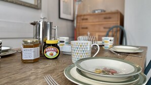 A dining table with a jar of honey, marmite, and a teapot.