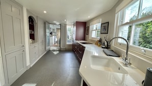 A modern kitchen with white cabinetry, a large window, and a built-in oven.