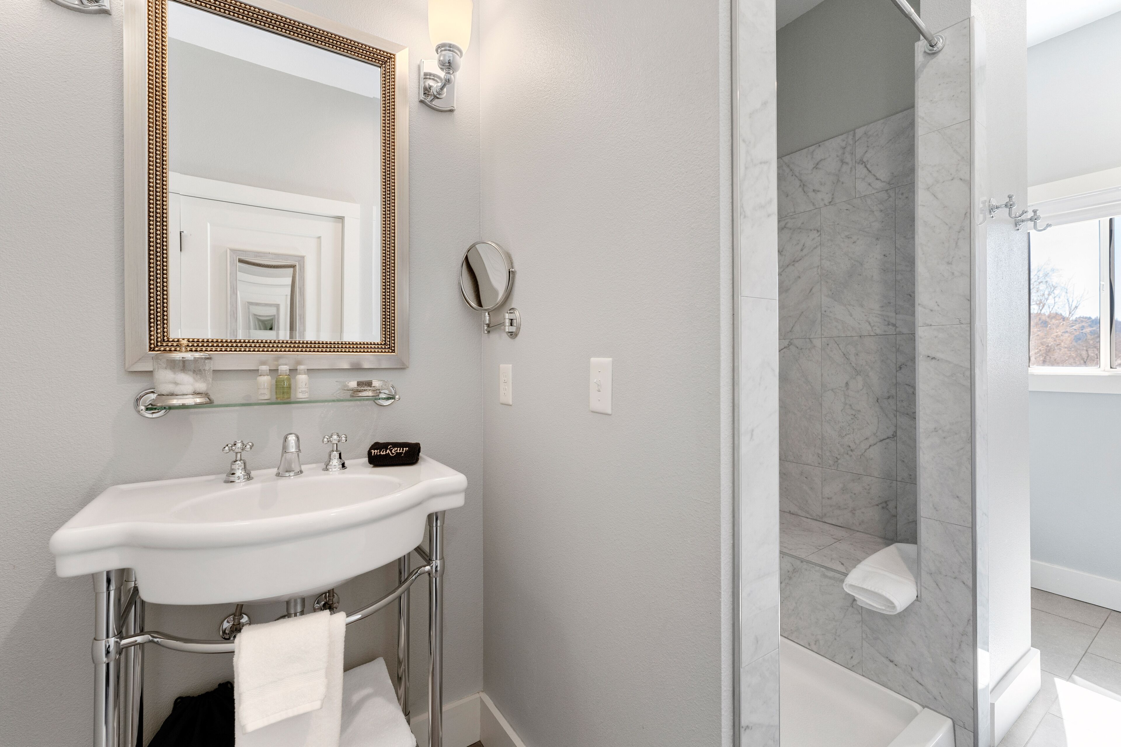 A bathroom with a white sink, a large mirror, a handheld showerhead, and a bathtub.