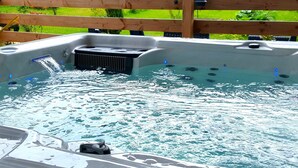A hot tub with a wooden deck and a grassy background. - L'horizon Holiday Apartment (Erquy)