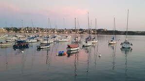 A marina with multiple boats docked, a lighthouse in the background, and a town across the water. - L'horizon Holiday Apartment (Erquy)
