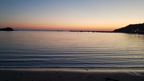 A beach with calm water, a distant shoreline, and a clear sky. - L'horizon Holiday Apartment (Erquy)